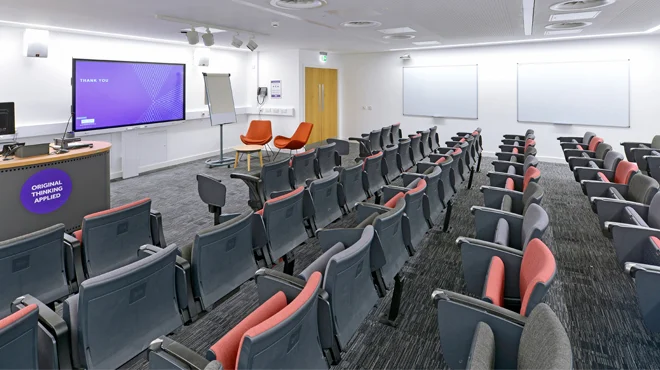 The 2.007 lecture theatre in AMBS, with a row of seating, a desk and a presentation screen