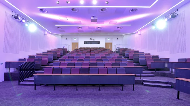 The G.003 lecture theatre in AMBS with tiered seating and purple lighting