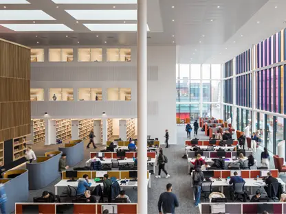 The Eddie Davies Library inside AMBS, with lots of desks, private pods and computers where students are working