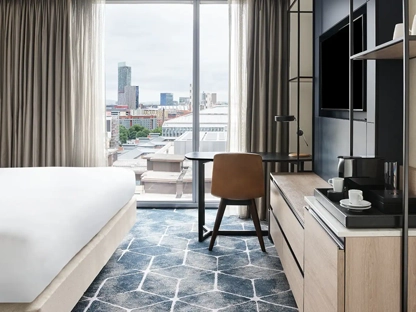 A room in the Hyatt hotel with a kingsize bed and desk in front of a big window with a view over Manchester city centre