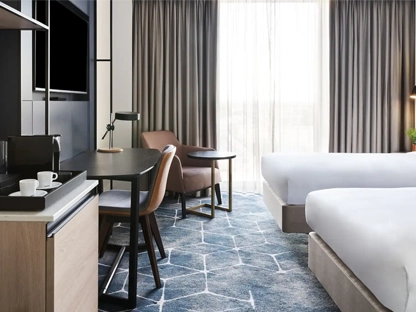 A room in the Hyatt hotel with two twin beds and desk and chair in front of a big window with lots of light