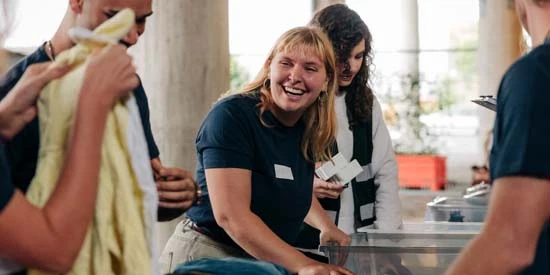 A female volunteer laughing with a colleague while sorting clothes at community service center