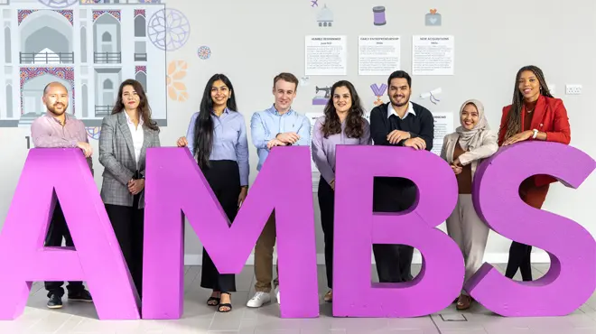 Members of the Full-time MBA student council stood in the AMBS reception in front of big pink 'A', 'M', 'B' and 'S' letters