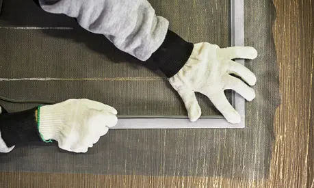 Hands of a worker at a factory making a mosquito net.