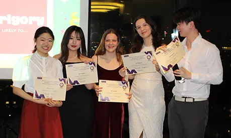 A group of five students posing for a photo with award certificates.