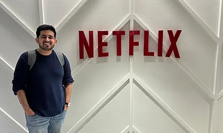 Armaan Raj Dua standing next to a large Netflix logo.