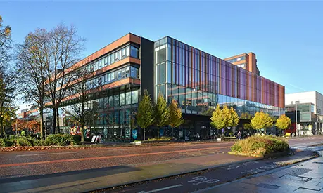 Alliance Manchester Business School building on Oxford Road at the University of Manchester, viewed from the street on a clear day.