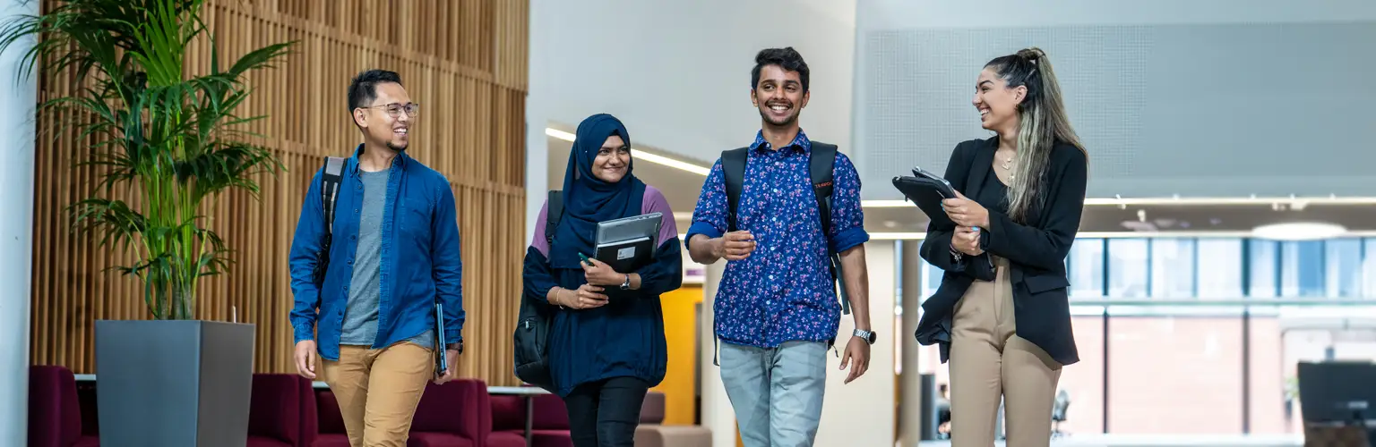 A group of university students walking through a wide corridor in their university