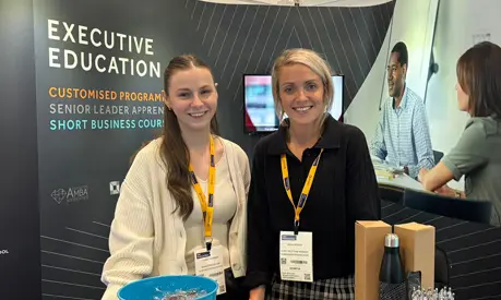 Two AMBS colleagues stood behind an exhibition stand