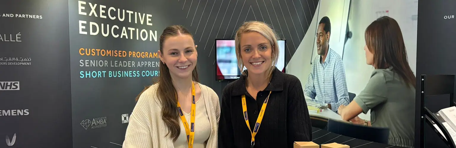 Two AMBS colleagues stood behind an exhibition stand