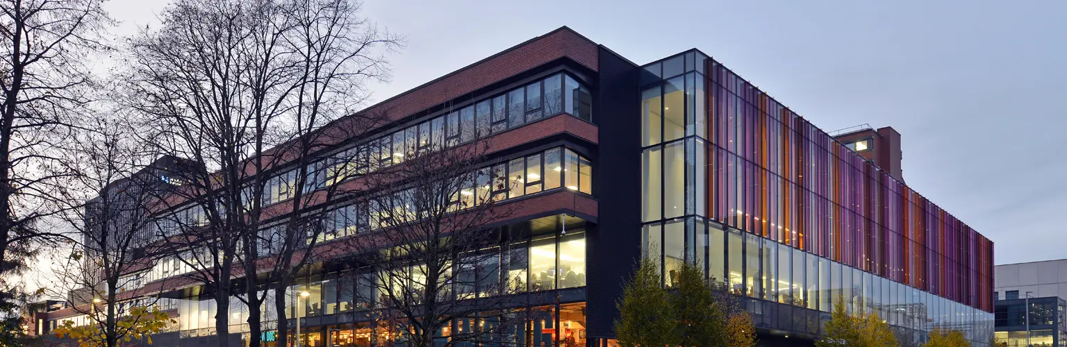 Alliance Manchester Business School building with a tree in front of it in the evening light