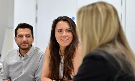 Three professionals engaged in a discussion during a meeting.