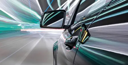Close up of a car's wing mirror in a tunnel with bright lights
