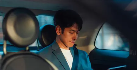 Asian male entrepreneur working on digital tablet while traveling by a car.