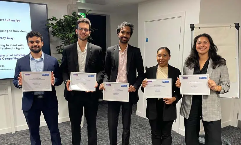 A group of five MBA students holding up certificates