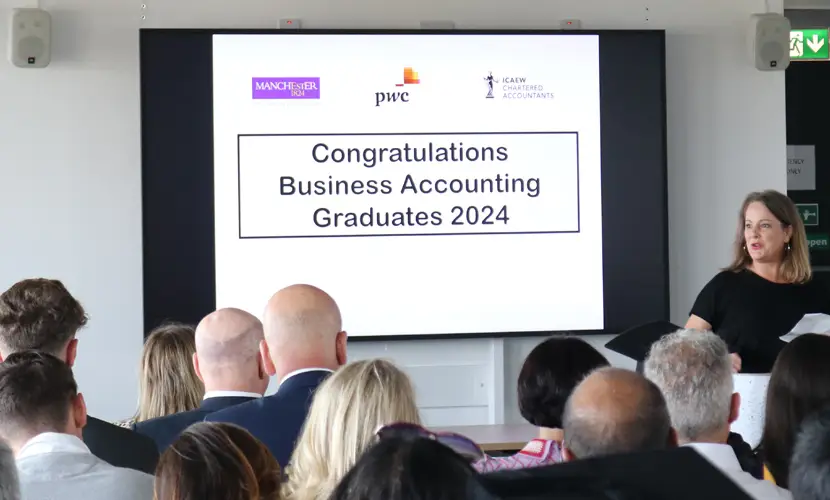 A room full of graduates looking at a presentation screen that reads 'Congratulations Business Accounting Graduates 2024'