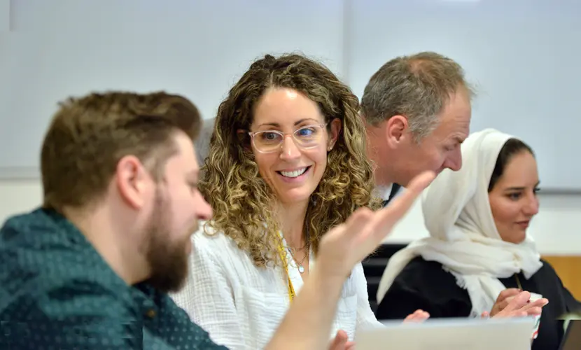 Two delegates in a classroom having a conversation while a tutor helps another delegate