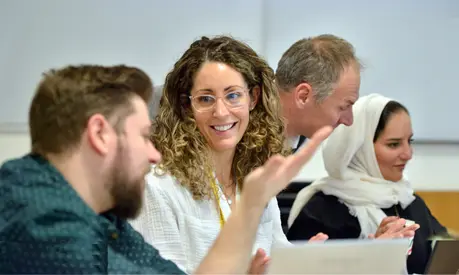 Two delegates in a classroom having a conversation while a tutor helps another delegate