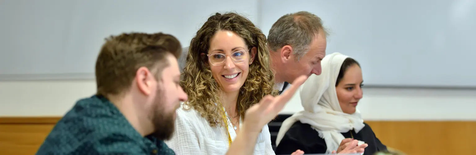 Two delegates in a classroom having a conversation while a tutor helps another delegate