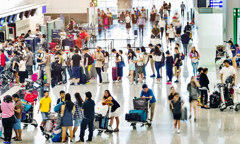 A large crowd of people waiting at a check-in desk in a busy airport