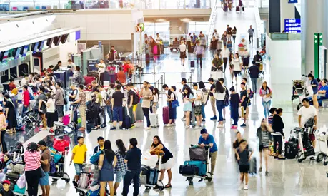 A large crowd of people waiting at a check-in desk in a busy airport