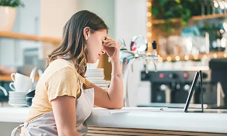 A young woman experiencing stress while working in a cafe.