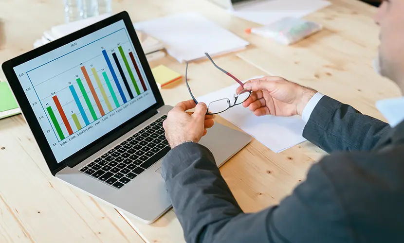 Business person looking at a bar chart on a laptop.