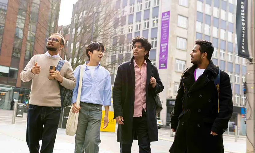 Four students walking through Manchester city centre.