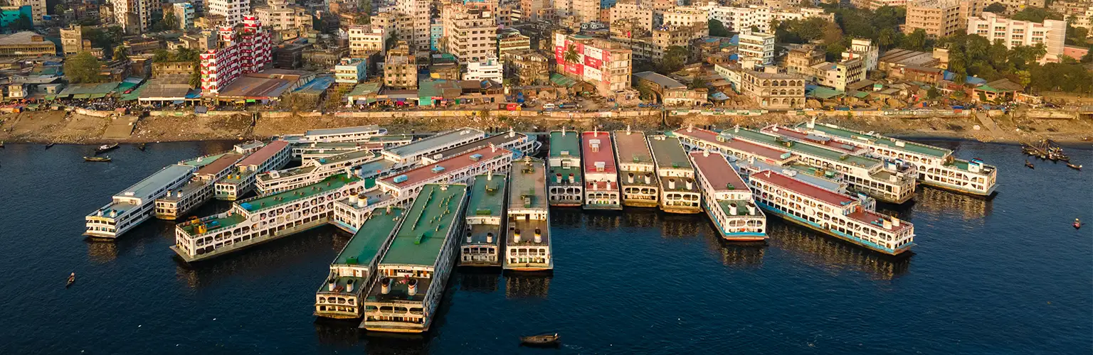 An aerial view of the Sadarghat Launch Terminal within the Dhaka city skyline.