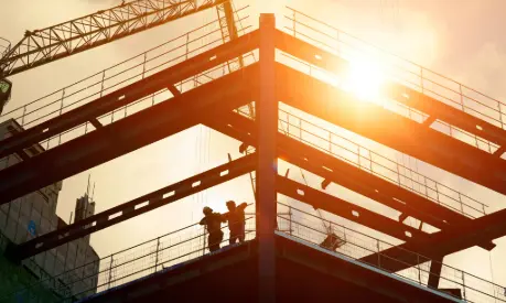 Construction workers silhouetted against the sun