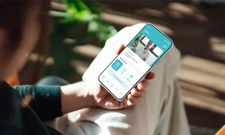 Over the shoulder view of a person holding their phone, having a video consultation with a doctor through an app