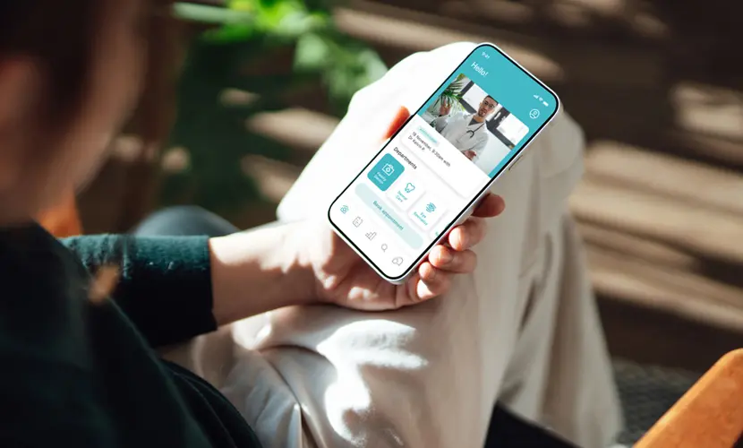 Over the shoulder view of a person holding their phone, having a video consultation with a doctor through an app